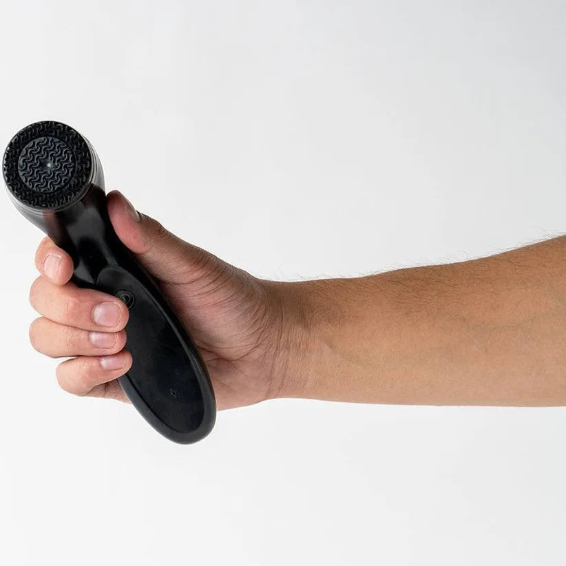 Hand holding a black LumiSpa device against a white background
