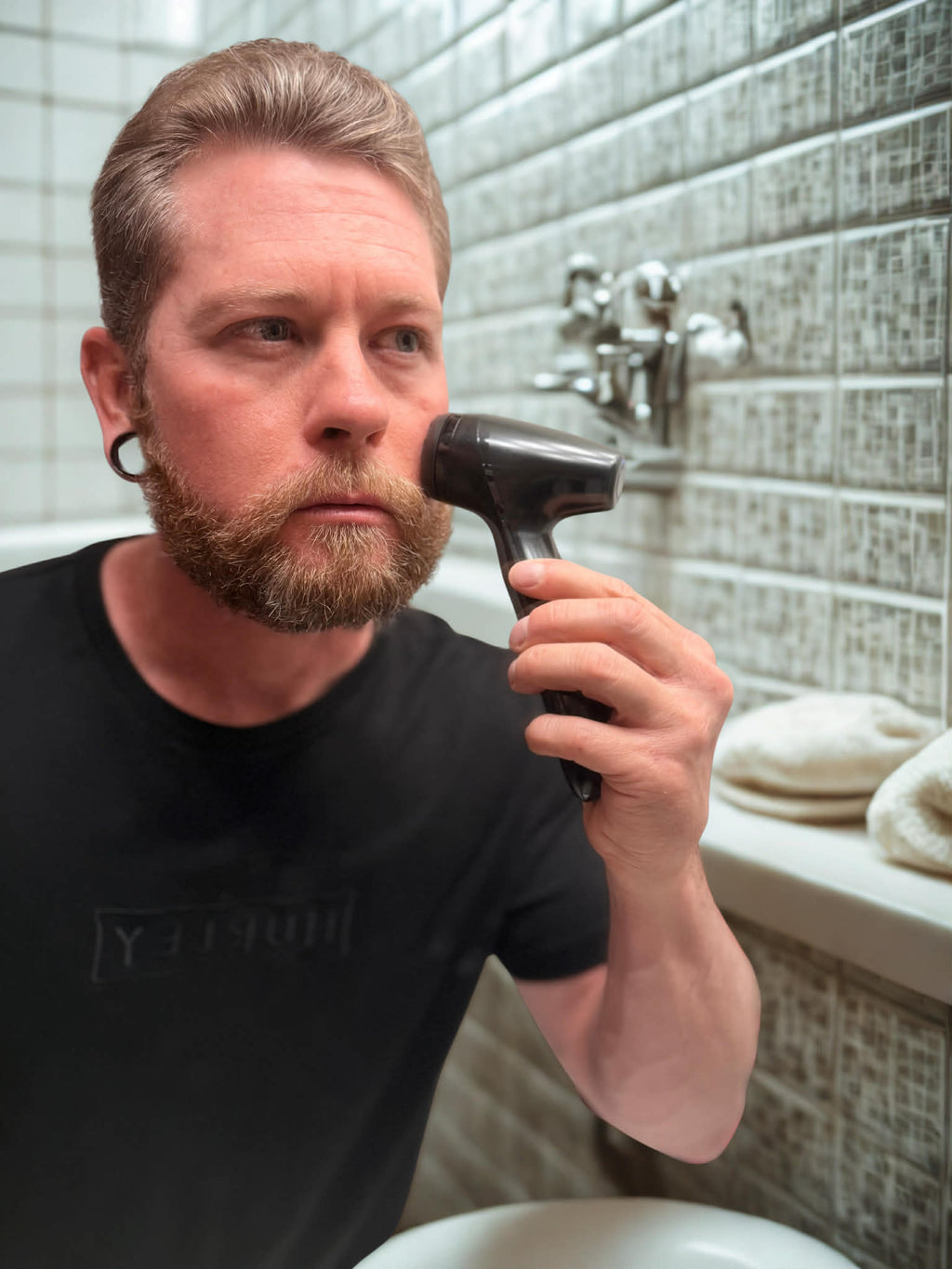 Man using a Black LumiSpa in a bathroom setting